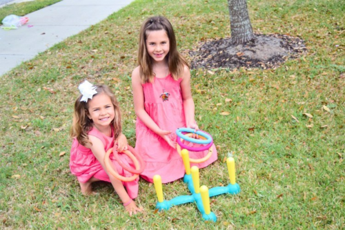 Two girls with ring toss game.