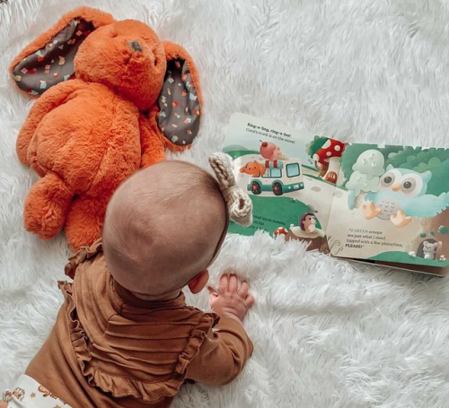 Baby with book and plush bunny.