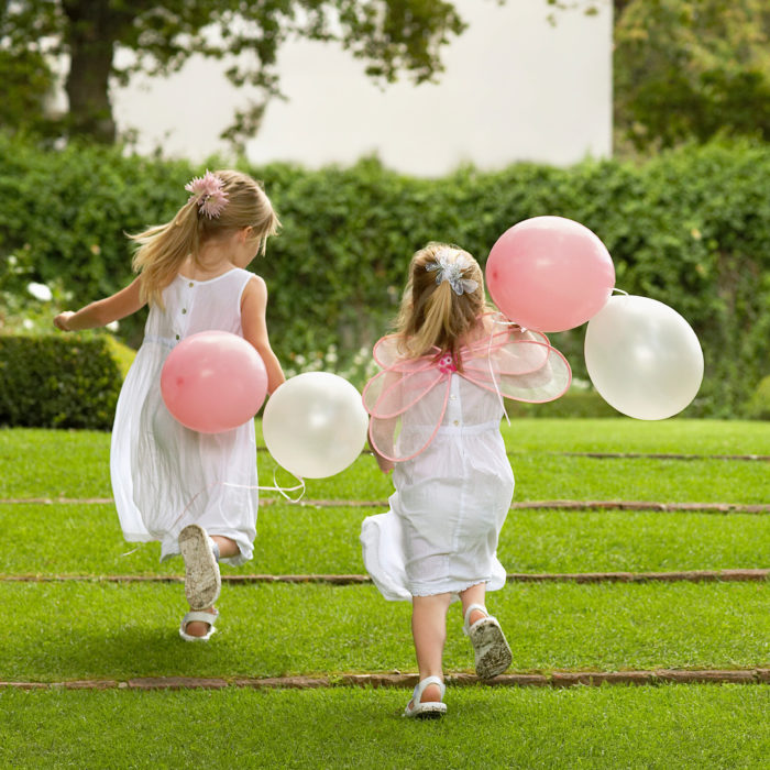 Two girls running with balloons.