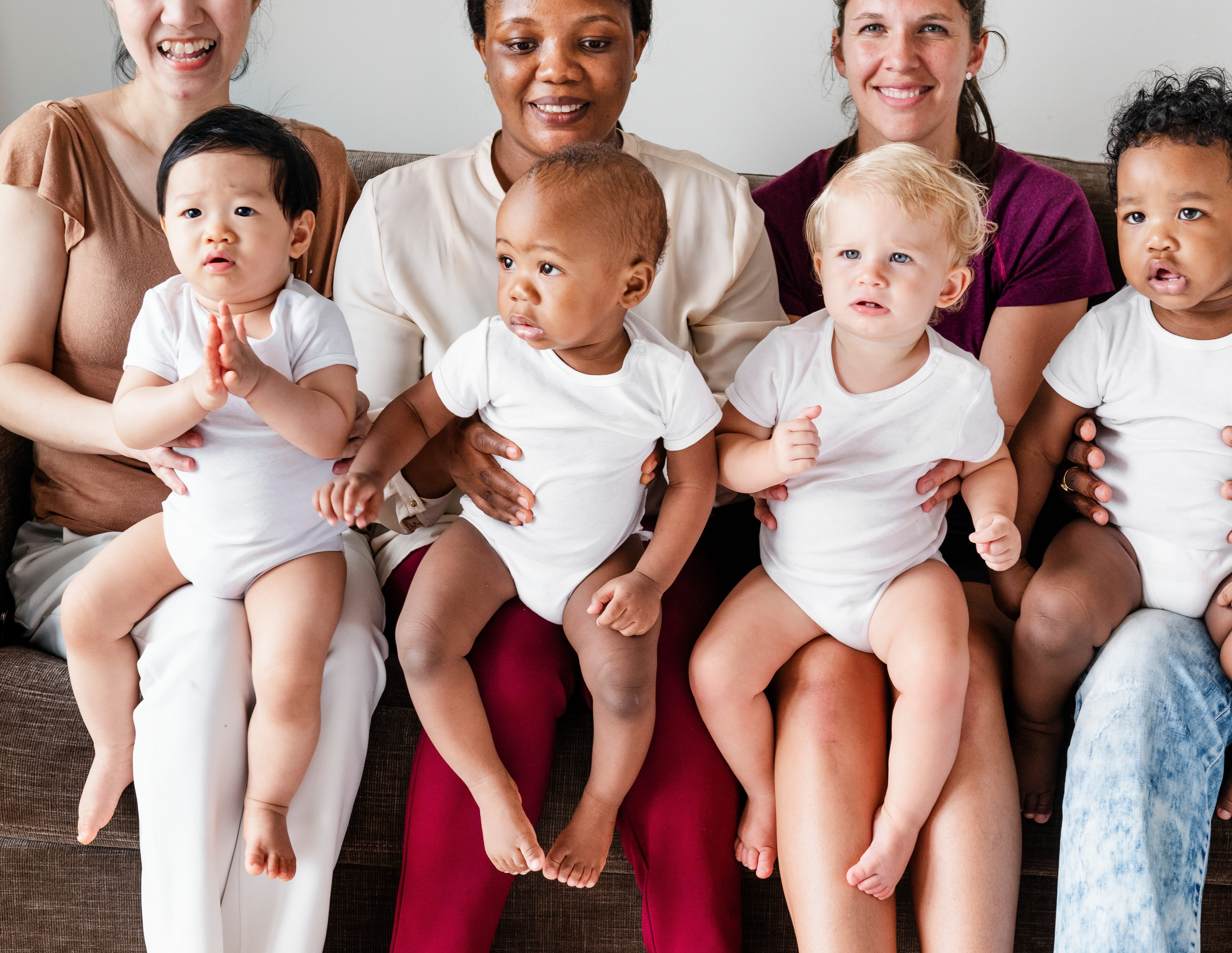 Four babies sitting on their parents' lap