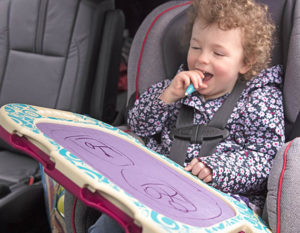 Smiling boy with a drawing board in a car.