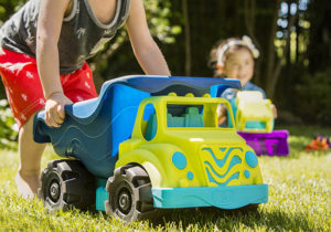Child pushing a large and colorful toy dump truck.