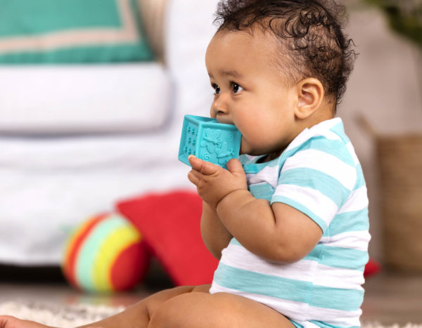Baby chewing on a baby block.