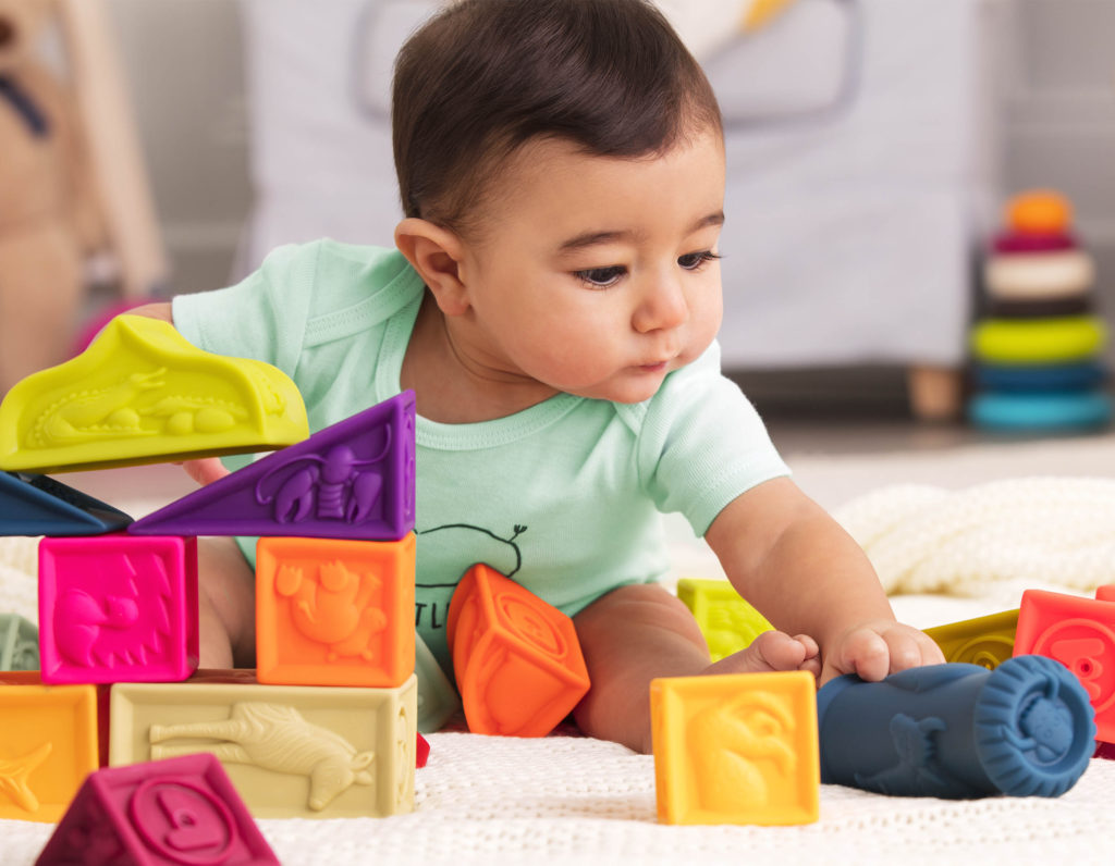 Baby sitting and playing with soft building blocks