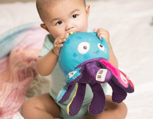 Baby holding on to a plush octopus toy.