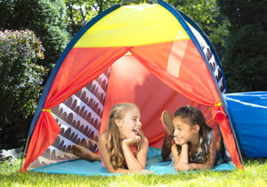 Two girls laughing in a tent outdoors.