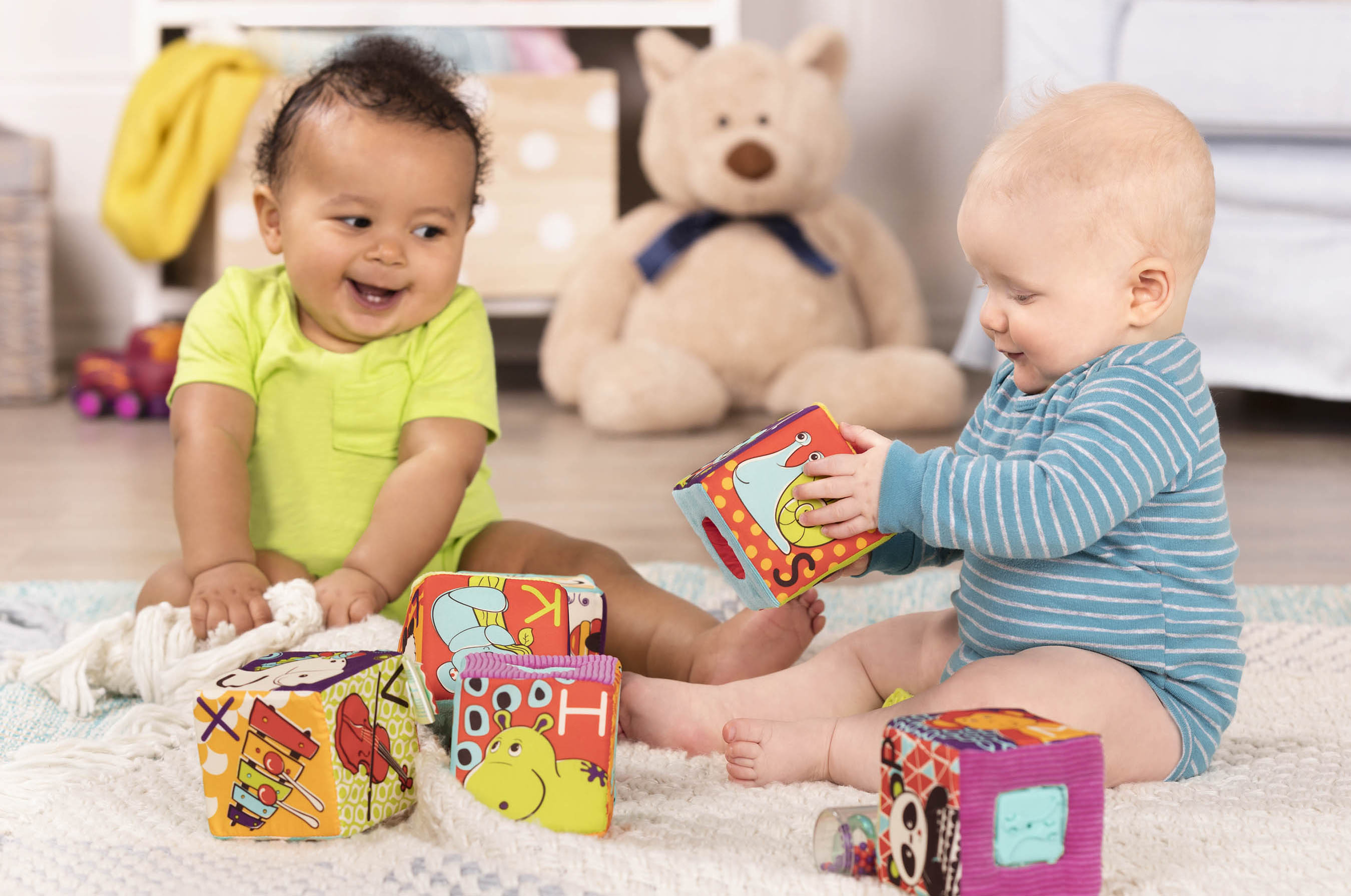 Two babies playing with soft blocks.