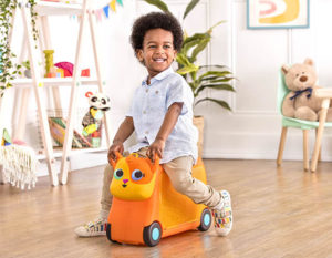 Smiling boy on ride-on cat suitcase.