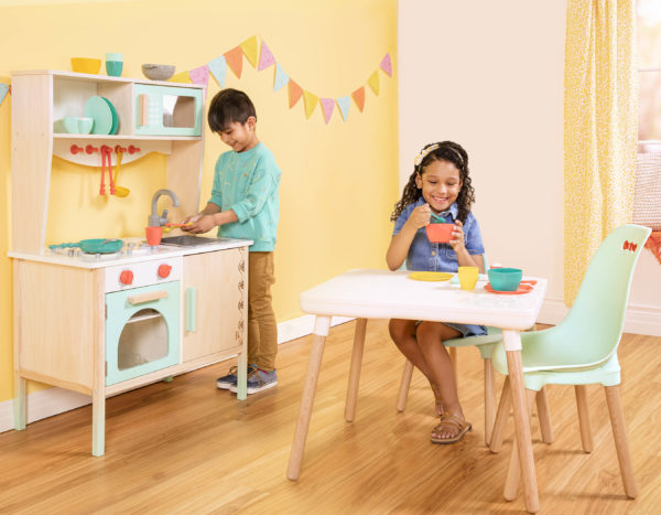Kids in play kitchen and sitting at a table.
