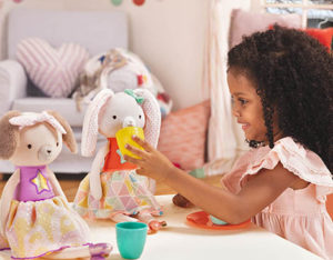 Girl at tea party with plush dolls.