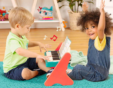 Toddlers playing on a toy piano.