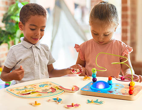 Two kids with wire maze and peg puzzle.