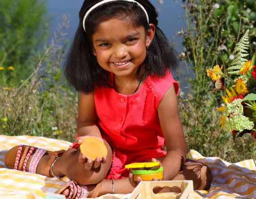 Girl with wooden play food.
