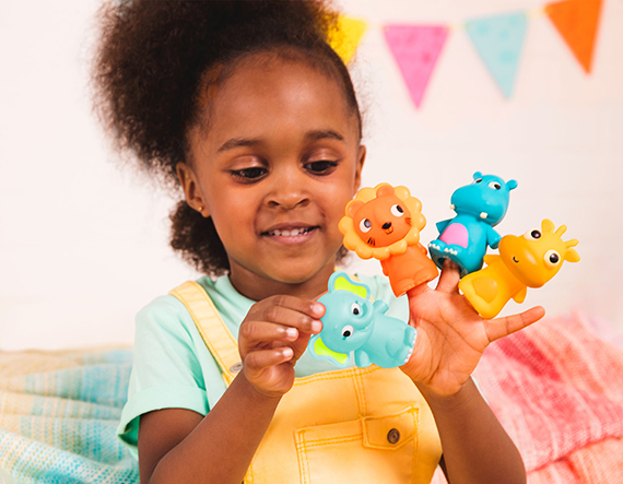 Smiling girl with four animal finger puppets on her hand.